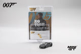 Mini GT Aston Martin DBS displayed with No Time To Die 007 blister packaging featuring Nomi artwork and the grey model positioned in front