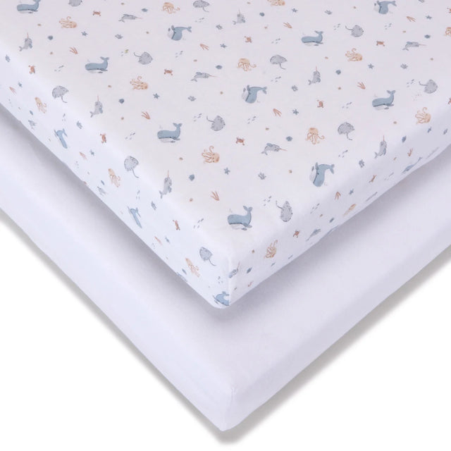 Fitted jersey travel cot sheet with Under the Sea pattern shown over a plain white sheet, highlighting the elasticated corner and layered fabric
