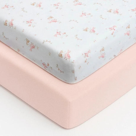 Close up corner view of the Baby Elegance travel cot jersey sheets showing the pink Little Ducks patterned fitted sheet layered over the plain pink fitted sheet, highlighting the fabric texture and elasticated fit