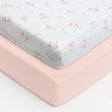 Two Baby Elegance fitted jersey travel cot sheets shown stacked, with a white sheet featuring a pink Little Ducks pattern placed on top of a plain soft pink sheet, photographed on a white background