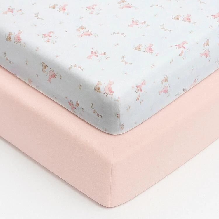 Stacked Baby Elegance travel cot jersey sheets with rounded fitted corners, showing the contrast between the white Little Ducks print sheet and the solid pink sheet on a white background