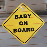 Babylo baby on board sign attached to a car rear window using a suction cup, yellow diamond sign with black border and baby on board text visible through glass