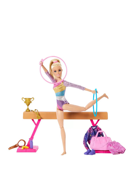 Barbie gymnast doll balancing on beam with hoop, trophy and accessories arranged around her