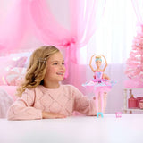 Barbie In The Nutcracker Clara Doll standing with both arms raised beside a smiling child in a pink room.
