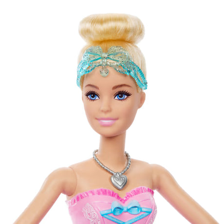 Close view of the Barbie In The Nutcracker Clara Doll with blonde hair in a bun, a blue bow headband, blue eyes and a heart necklace.