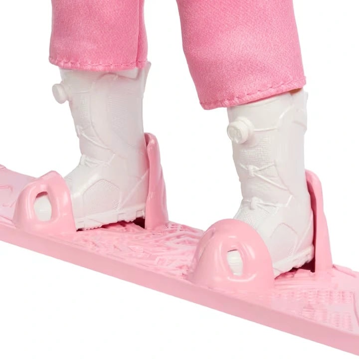 Close-up of Barbie Snowboarder Doll's white boots secured between raised pink foot holders on a textured pink snowboard, with the bottoms of her pink trousers visible.