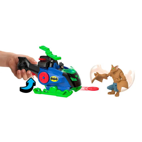 Hand pressing the Batcopter launcher with a red disc aimed towards the Man Bat figure