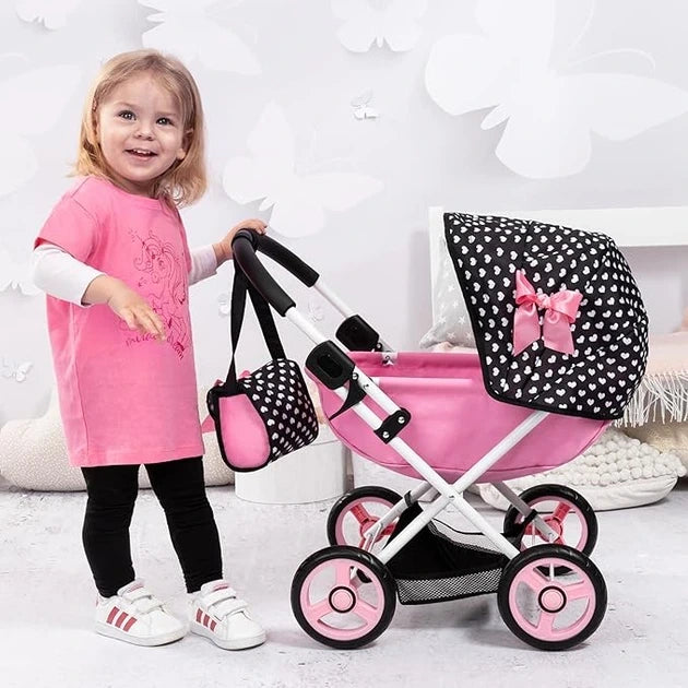 Child standing beside Bayer Design Dolls Pram Cosy pink doll pram with black polka dot hood