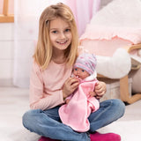 Child holding Bayer Reborn baby doll with pink blanket and dummy