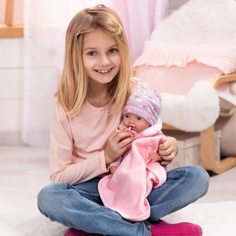 Child holding Bayer Reborn baby doll with pink blanket and dummy