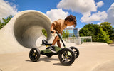 Child with BERG Buzzy Green pedal go-kart outdoors beside a large concrete tunnel