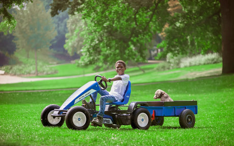 Child pulling BERG Steel Trailer XL behind blue go-kart in park – Ireland