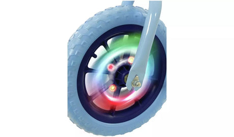 Close-up of the Bluey Light Up Balance Bike wheel showing illuminated red and green LED lights glowing through the dark navy spokes and light blue tyre