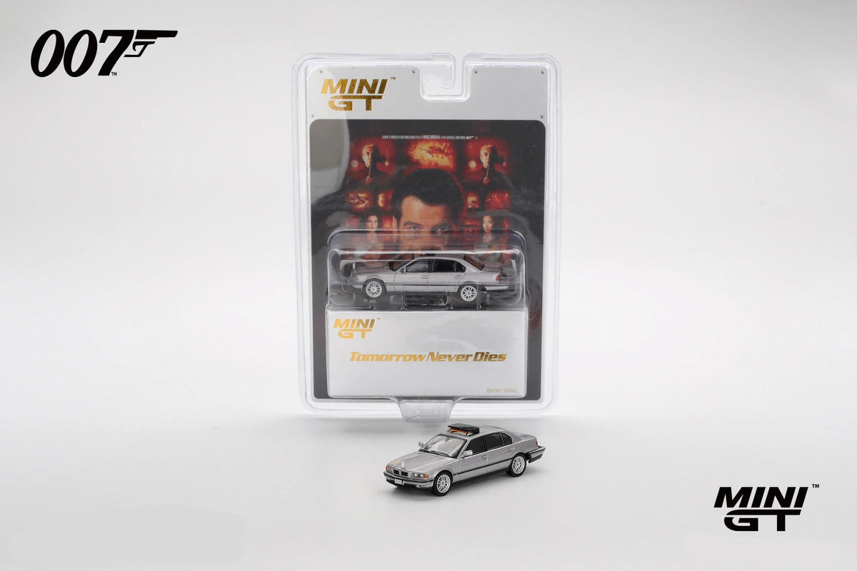 Mini GT BMW 750IL displayed in front of its Tomorrow Never Dies 007 blister packaging with film artwork and the silver model visible inside the pack
