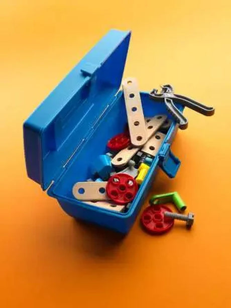 Open turquoise BRIO Builder toolbox containing wooden strips, red wheels and grey toy tools on an orange background, with loose components beside it.
