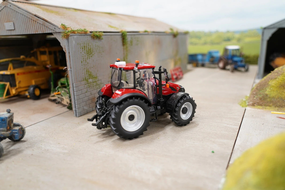 Britains Case Farmall 120 C farm toy tractor shown side on in a model farmyard with sheds visible