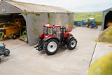 Britains Case Farmall 120 C farm toy tractor shown side on in a model farmyard with sheds visible