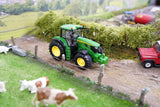 Britains John Deere 6M 240 farm toy tractor on a model lane with a red trailer and cows visible