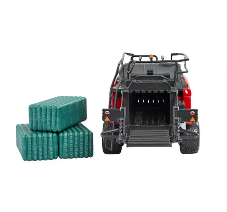 Rear view of Britains Case IH LB434R XL large baler model with open bale exit chamber, visible rear rollers, safety decals, twin wheels, and three green rectangular bales placed to the side on a white background