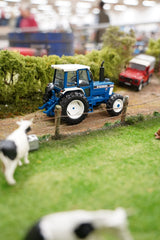 Britains 1:32 Ford 8210 Tractor 43418 on a model farm scene beside hedges and cattle 
