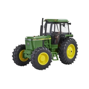 Britains John Deere 4450 tractor 1:32 scale model shown from the side with green bodywork, yellow wheels, large tread tyres, cab glazing and exhaust stack on a white background