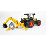 Bruder 02338 yellow rear excavator arm mounted on a green Claas tractor, showing its black digging bucket lowered, separate grey grab and folding stabiliser legs.