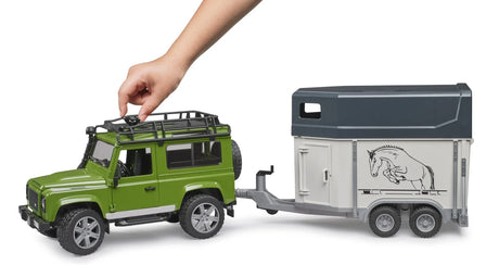 Bruder 1:16 Land Rover Defender farm toy with horse trailer and hand turning the steering wheel