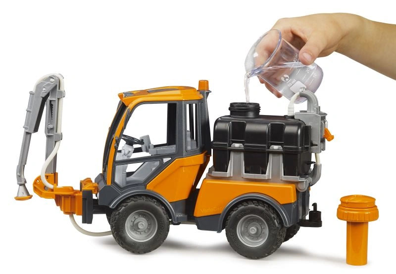 Bruder VarioCar 02692 black water tank being filled from a measuring jug, with the orange pump plunger removed and placed beside the vehicle.