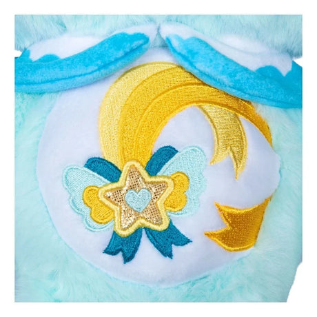 Close-up of Care Bears Kindness Keepers Wish Bear belly badge featuring a yellow shooting star, turquoise decorative bow, embroidered star ornament and gold accents on a white background.