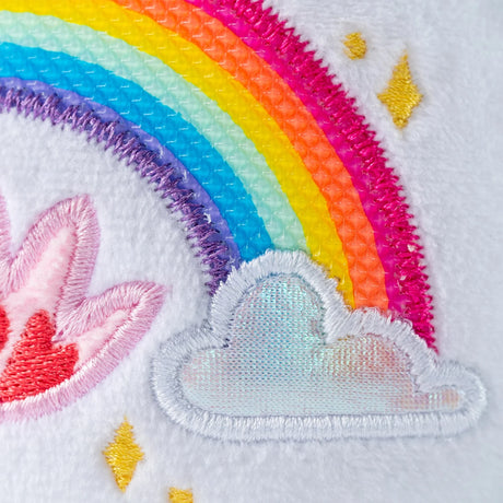 Close-up of Sweet Serenity Bear's rainbow belly badge showing colourful textured rainbow stripes, embroidered pink hearts, white clouds and yellow stars.