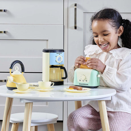 Child playing with the Casdon Morphy Richards Kitchen Set toaster, kettle, coffee maker and play food on a table