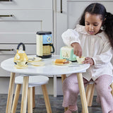 Child using the toaster from the Casdon Morphy Richards Kitchen Set beside the kettle, coffee maker, cups and plates
