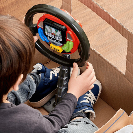 Close view of a child holding the Casdon Sat Nav Steering Wheel inside a cardboard car