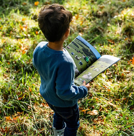 Child reading Tractor Ted Look and Find Farm Book outside in Ireland