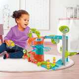 Smiling toddler playing with Clementoni Baby Fun Garage featuring colourful ramps and cars on a play mat in Ireland