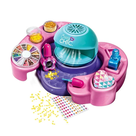 Clementoni Crazy Chic nail art kit showing the turquoise nail dryer on its pink and purple station, two nail polish bottles, yellow glitter, decorative nail pieces and sticker sheets.