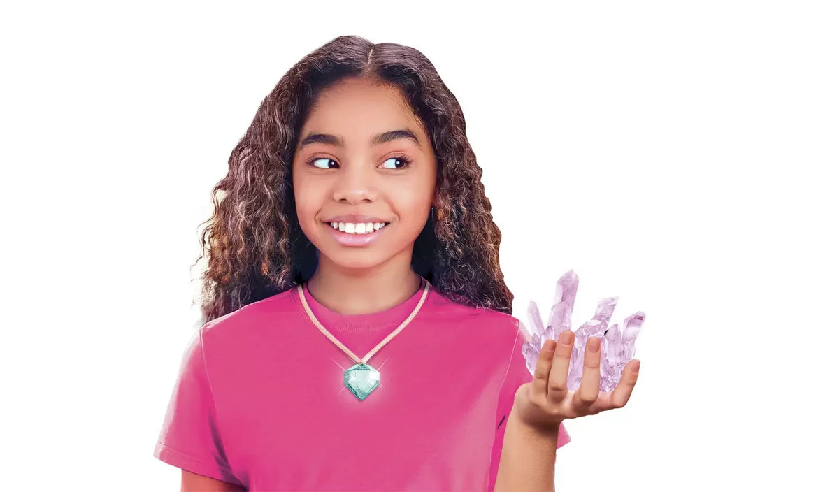 Girl wearing a pink T-shirt and green gemstone pendant necklace, holding a cluster of pale purple crystals against a white background.