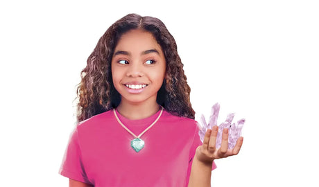 Girl wearing a pink T-shirt and green gemstone pendant necklace, holding a cluster of pale purple crystals against a white background.