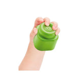 Close-up of a hand squeezing a flexible green Soft Clemmy building block against a white background.
