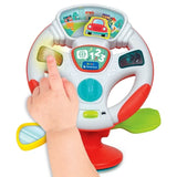 Close-up of a child's hand pressing the yellow light panel on the Baby Clementoni Steering Wheel, showing the illustrated car dashboard and colourful steering controls.