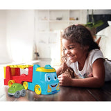 Young girl lying on a wooden floor beside the blue and red Clementoni Tumbling Car Transporter and its green tumbling car.