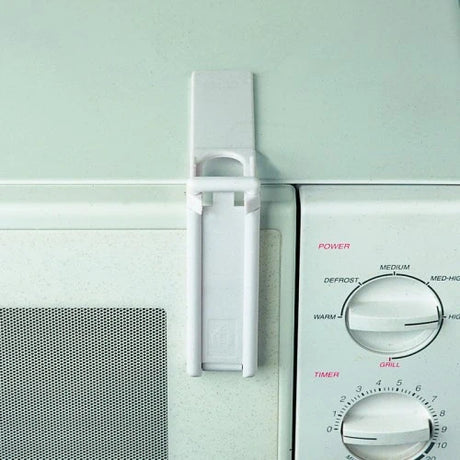 Clippasafe Microwave Oven Lock fitted to a white microwave door, showing press to lock mechanism secured between door and frame