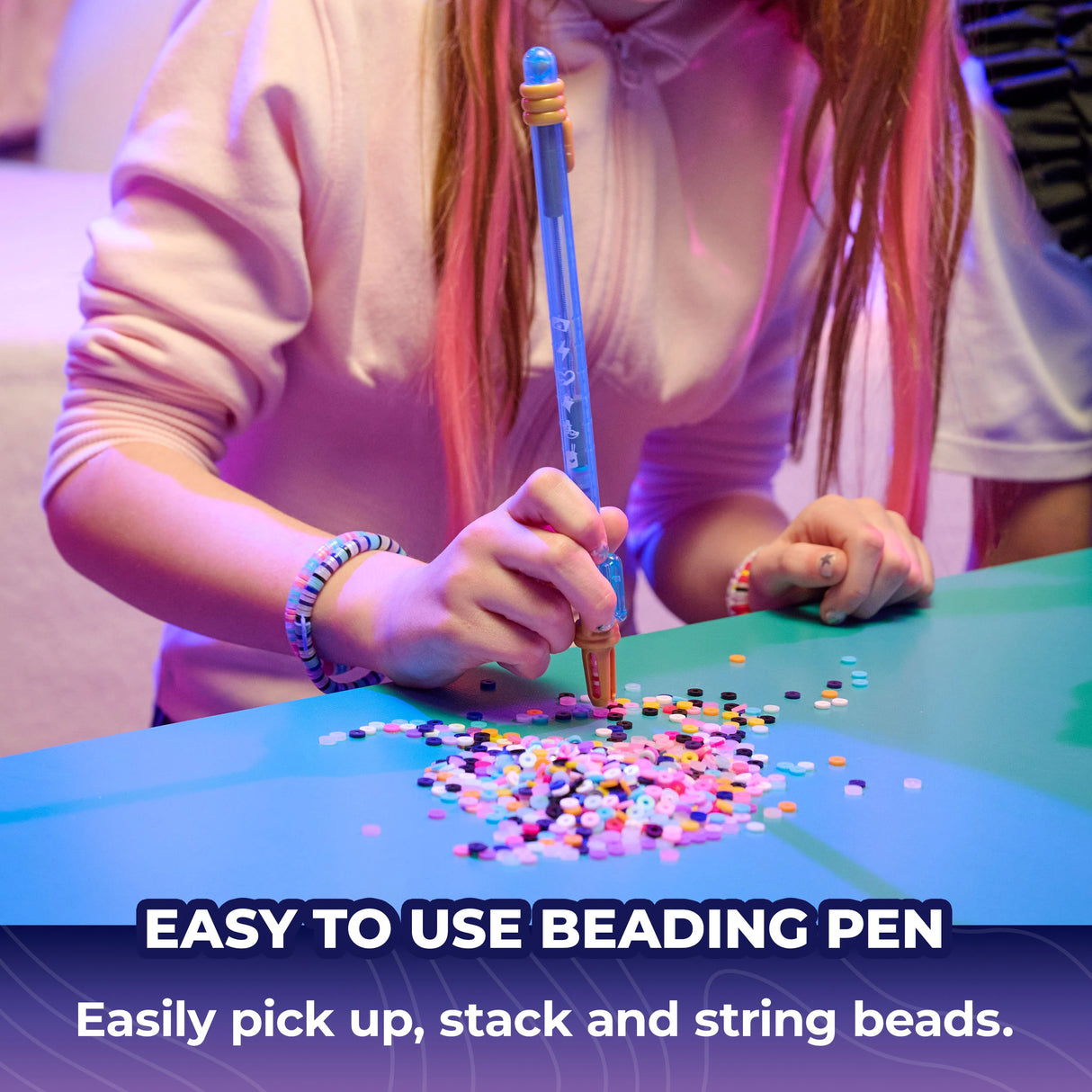 Child using the blue beading pen with loose coloured beads and a finished bracelet on the wrist