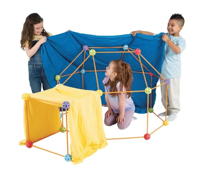 Three children with a Crazy Forts structure assembled from orange rods and colourful connectors, with blue and yellow fabric draped over the frame.