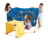 Three children with a Crazy Forts structure assembled from orange rods and colourful connectors, with blue and yellow fabric draped over the frame.