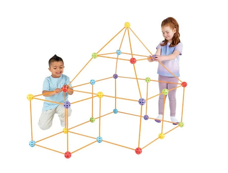 Two children assembling a house-shaped Crazy Forts structure using orange rods and red, yellow, blue, purple and green connector balls.
