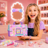 Smiling girl holding the pink, turquoise and purple Creamy Deco Activity Case by its handle, with decorating cream tubes, piping nozzles, colourful finished accessories and charms arranged on the table.