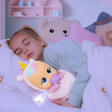 Young girl sleeping in bed while cuddling Cry Babies Luna, with the doll's white wings illuminated beside her pillow.