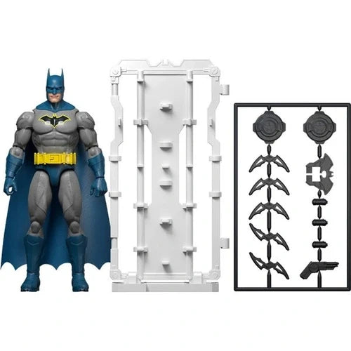 DC Batman blue and grey action figure displayed beside a tall white weapons rack and a black accessory frame containing Batarangs, circular pieces and other miniature weapons.