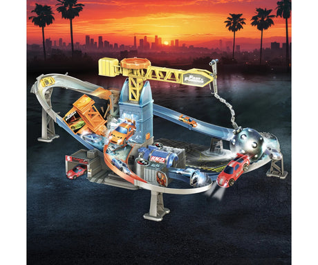 Fast & Furious Wrecking Crash Course illustrated stunt scene with a sunset skyline, a yellow crane, swinging wrecking ball and cars racing around the track.